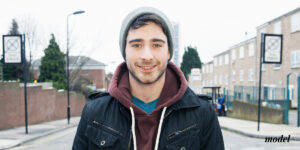 Young Man Standing in City Street with Slight Smile
