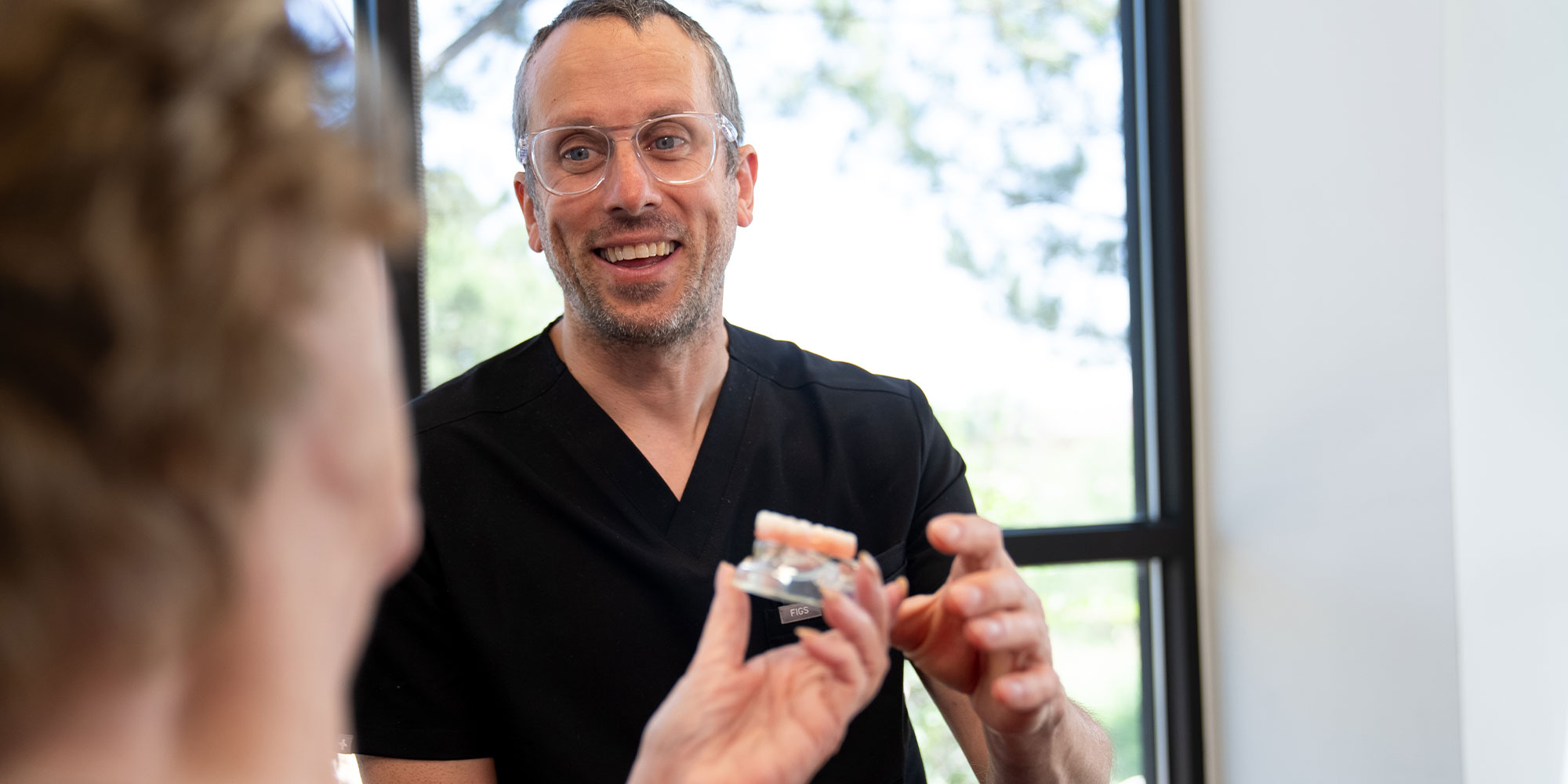 Doctor handing over a model a full arch to Patient