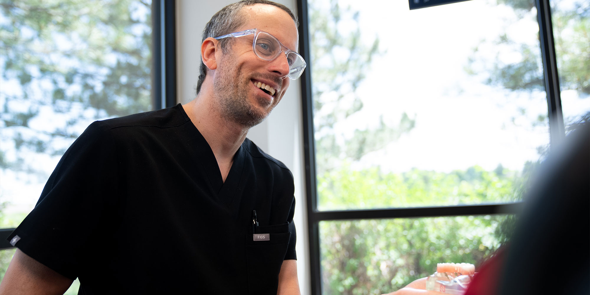 Doctor holding up a model full arch dental implants showing patient