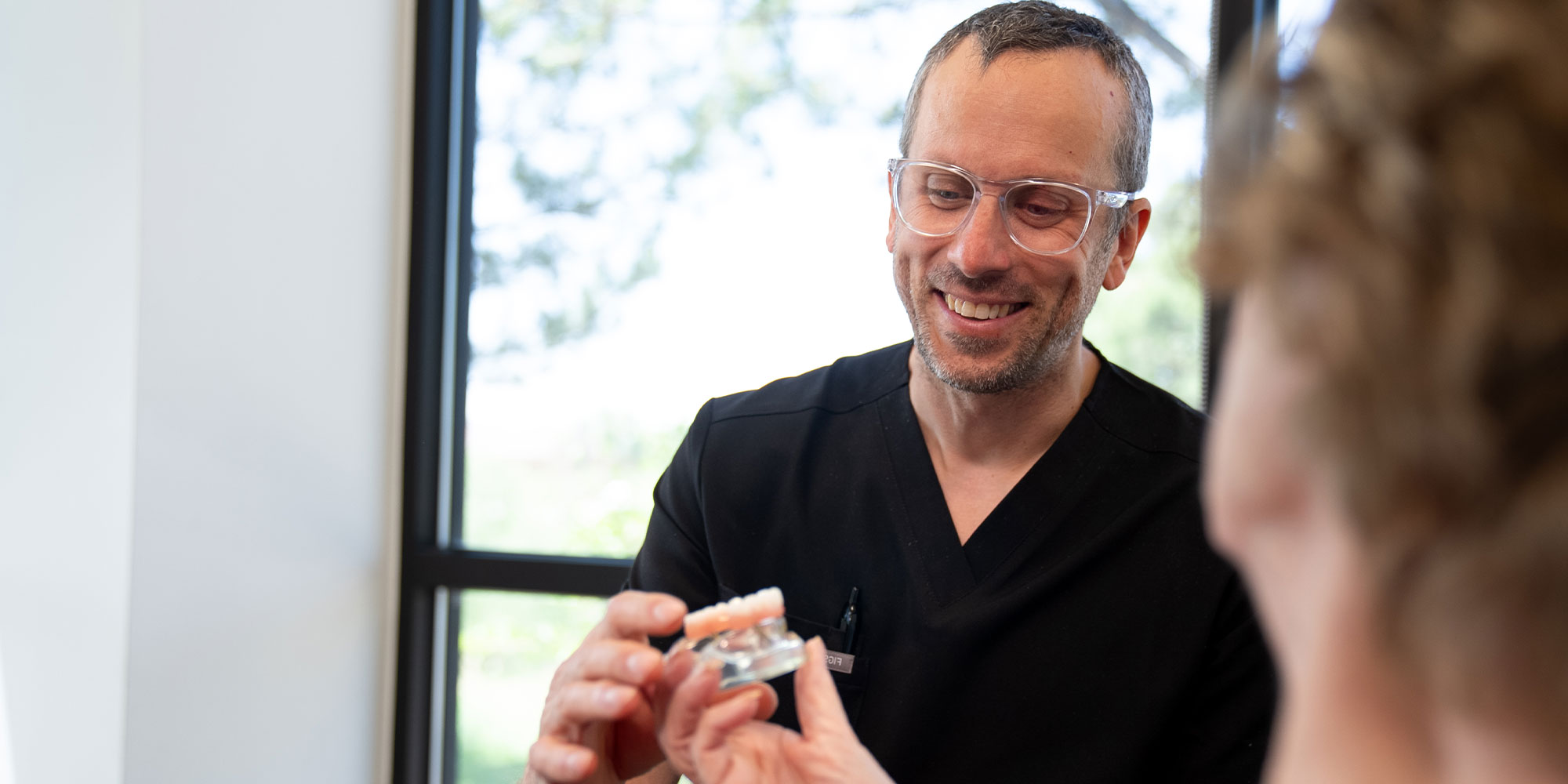 Paitent holding full arch of dental implants